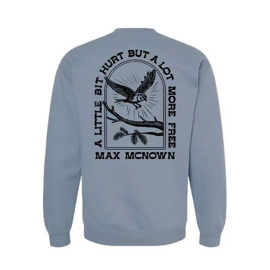 Blue crewneck with bird and tree branch design. back text reads "A Little Hurt But A Lot More Free Mac McNown". front text reads "A Lot More Free"