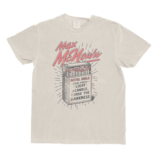 Ivory tee featuring matchbox design with text that reads "Hotel Bible - Strike A Match Light A Candle, Curse The Darkness"