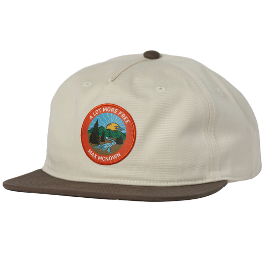 two tone white and brown hat with orange patch featuring a nature landscape design